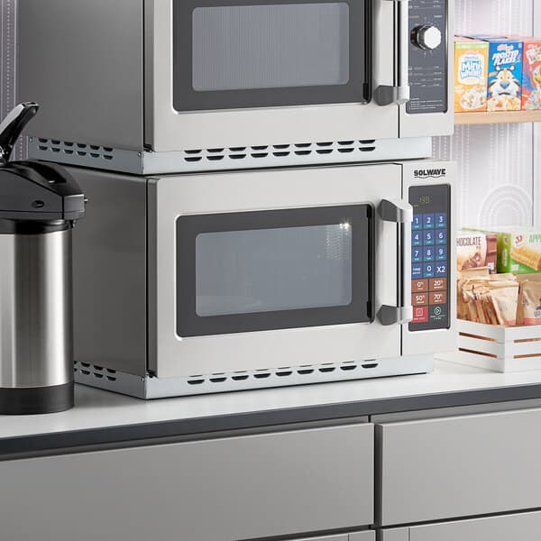 Two Solwave stackable commercial microwaves on a counter in a professional kitchen.